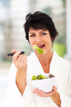 healthy middle aged woman eating green salad