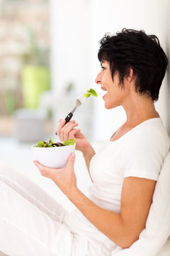 beautiful middle aged woman eating salad at home