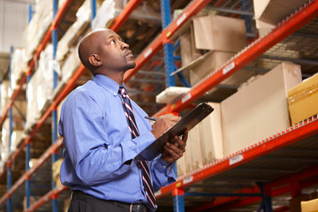 Businessman With Clipboard In Warehouse