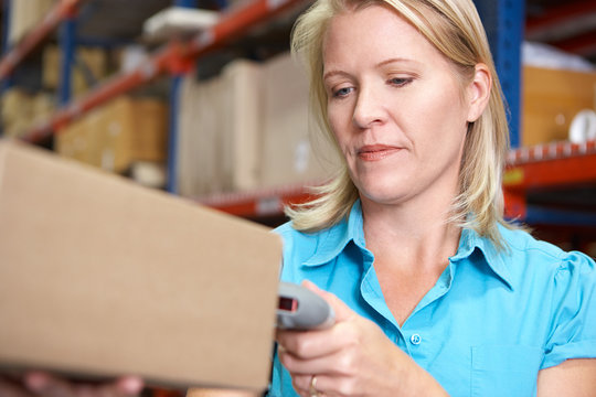 Businesswoman Scanning Package In Warehouse
