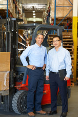 Portrait Of Businessmen With Fork Lift Truck In Warehouse