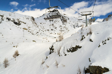 chairs on ski lift above a rocky mountain in winter