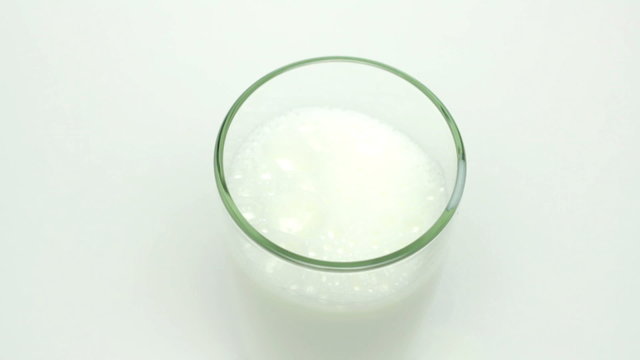 Milk filling the glass on the white background