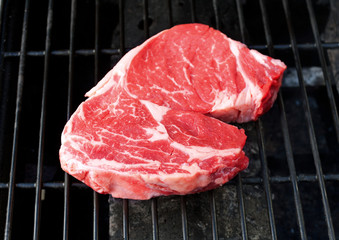 Raw steak cooking on a grill.
