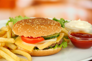 Tasty cheeseburger with fried potatoes, on bright background
