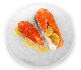 Pieces of red fish on ice in plate isolated on white