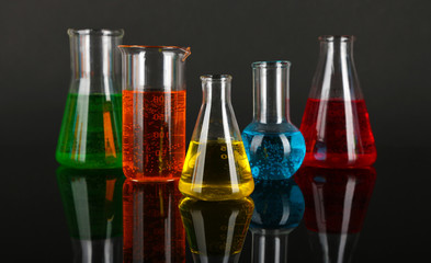 Test tubes with colorful liquids on dark grey background
