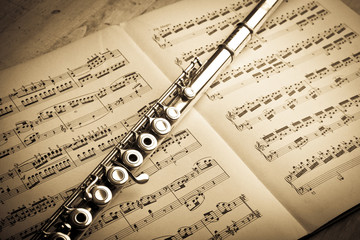 Silver flute on an ancient music score background