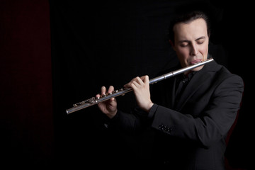 professional flutist musician playing flute on black background