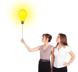 Happy women holding a light bulb balloon