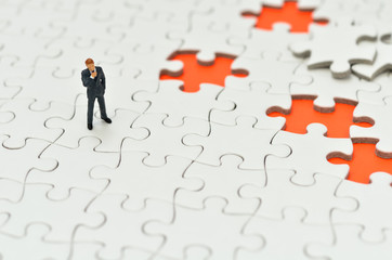 オレンジ色背景のジグソーパズルとビジネスマン
