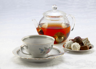 Cup on a saucer, teapot and chocolates