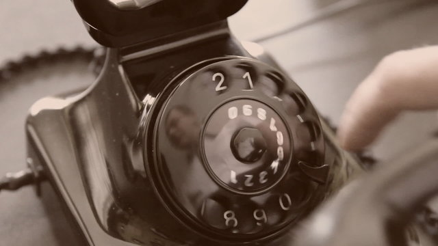 Vintage black telephone. Man dials Sepia