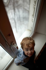 Smiling boy sitting on the windowsill.