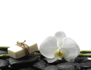 Fototapeta na wymiar Handmade soap and white orchid with bamboo glove on pebbles