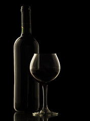 Red wine bottle and glass on black background