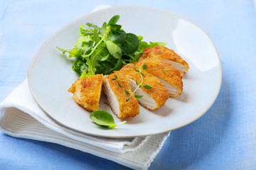 fried, breaded chicken fillet with fresh salad