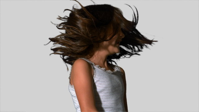 Little girl tossing her hair on white background