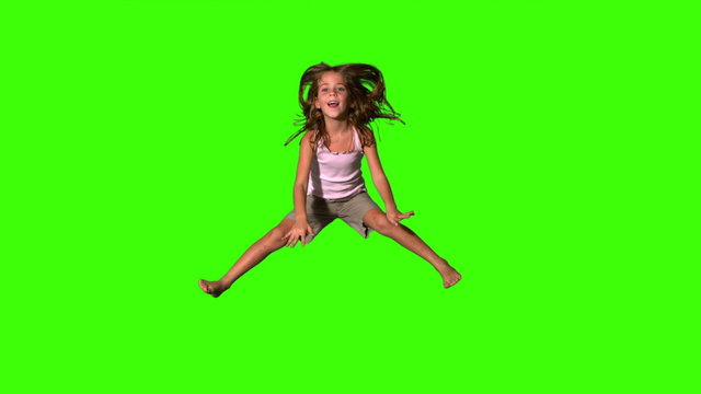 Happy girl jumping up and down on green screen