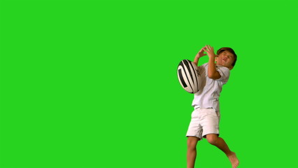 Happy little boy jumping and dropping rugby ball - Powered by Adobe