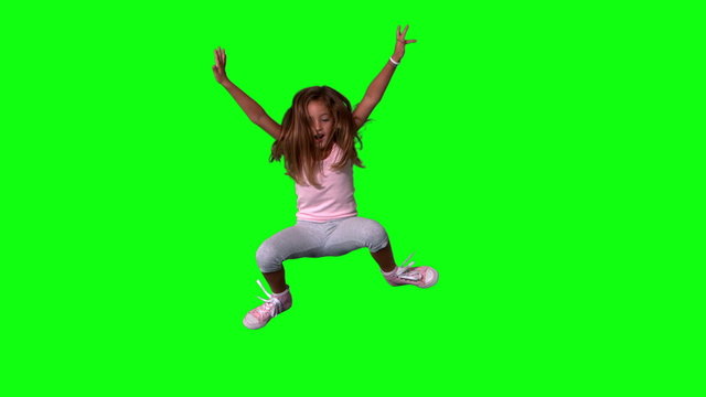 Cute little girl jumping with limbs outstretched on green screen