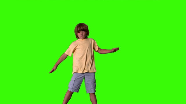 Little boy jumping with limbs outstretched on green screen