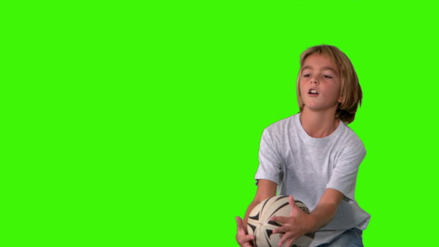 Boy catching rugby ball on green screen