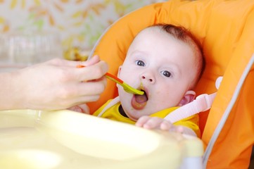 The five-months baby is fed by puree from a spoon