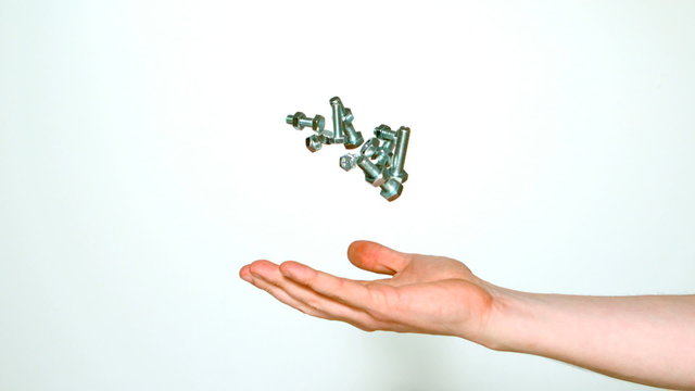 Mans hand tossing screws and bolts