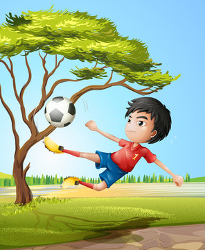 A boy playing soccer at the road