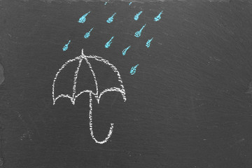 Chalk drawing of an umbrella and rain drops on slate