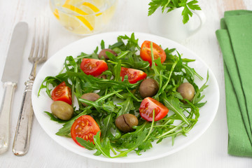 rucola with tomato and olives on the plate