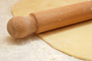 Detail of a wooden rolling pin on rolled out pastry