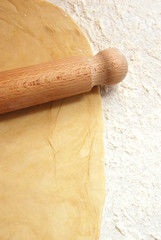 Portrait image of pastry being rolled out on a floured surface