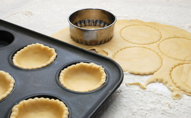 Pastry circles cut and lining a metal bun tin