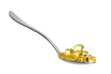 Fish oil capsules on a teaspoon isolated on white background