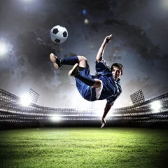 Fototapete Fußball Fußballspieler, der den Ball schlägt