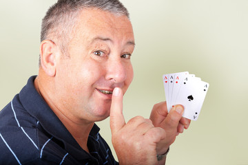 Man with four aces holding finger to mouth