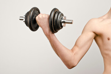 The before photo…. Arm of a slim young man lifting big weights.