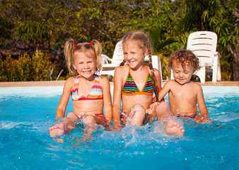 two little girls and little boy playing in the pool