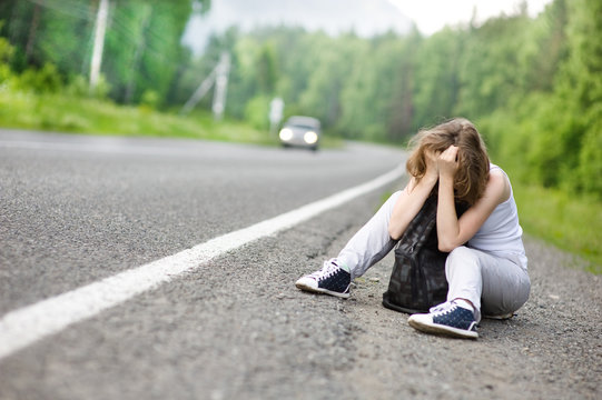 the sad girl hitchhiking along a road