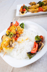 buttered rice topped with chicken kebab and vegetables on a side