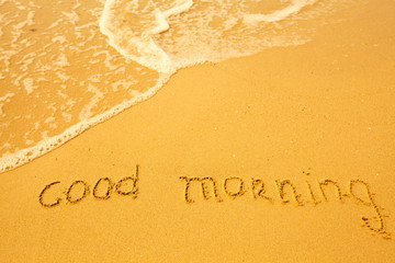 Good morning - written in sand on beach texture.
