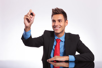 man at desk writes on imaginary screen