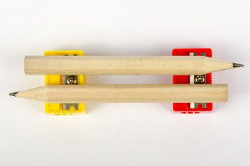 Two wooden pencils with red and yellow pencil sharpeners