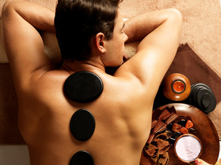 man having stone massage in spa salon