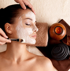 Spa therapy for woman receiving facial mask