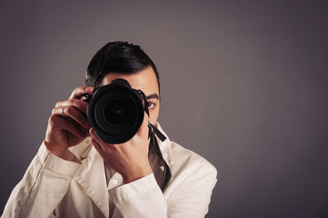 Man holding camera over dark background.