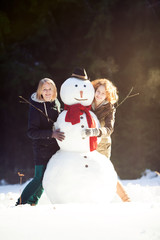 Two young women hugging snowman