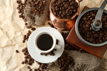 Cup of coffee, pot and grinder on beige background